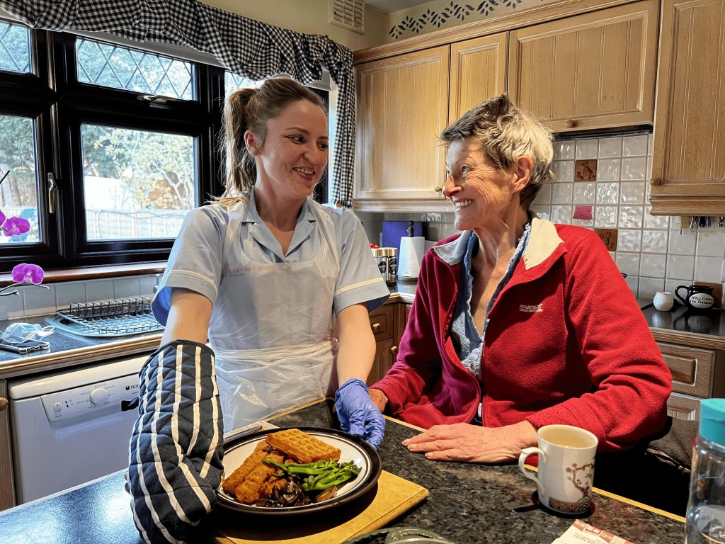 nurse making and serving food to lady in a red fleece 