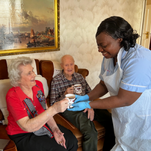 nurse providing cup of tea to an elderly couple