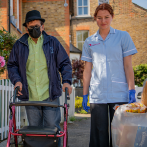 nurse and patient in zimmer frame walking down the street