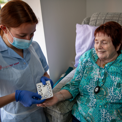 nurses providing medication to an elderly female patient 