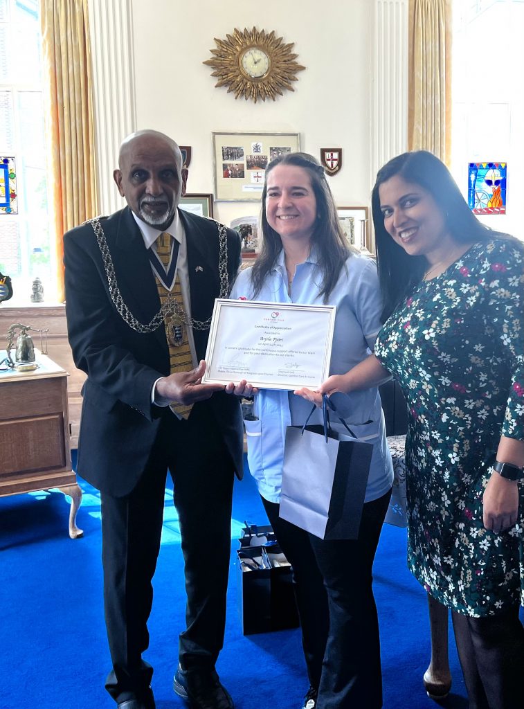 Mayor of the Royal Borough of Kingston Upon Thames, Cllr Yogan Yoganathan handing an award to Shamsah and her comfort care team 
